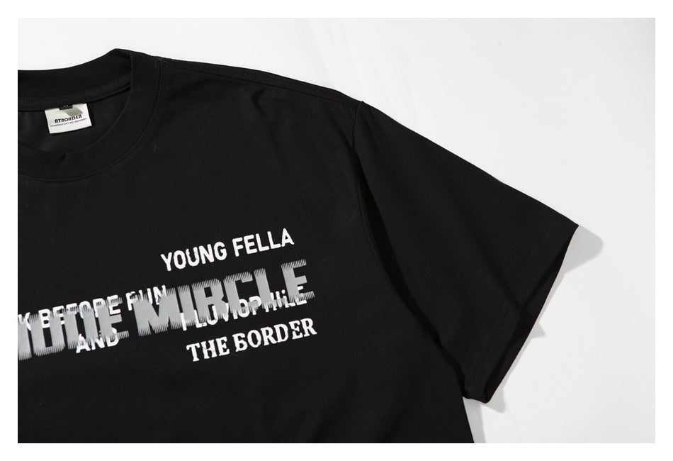 Close-up of a black T-shirt showing its short sleeve and part of the layered chest text.
