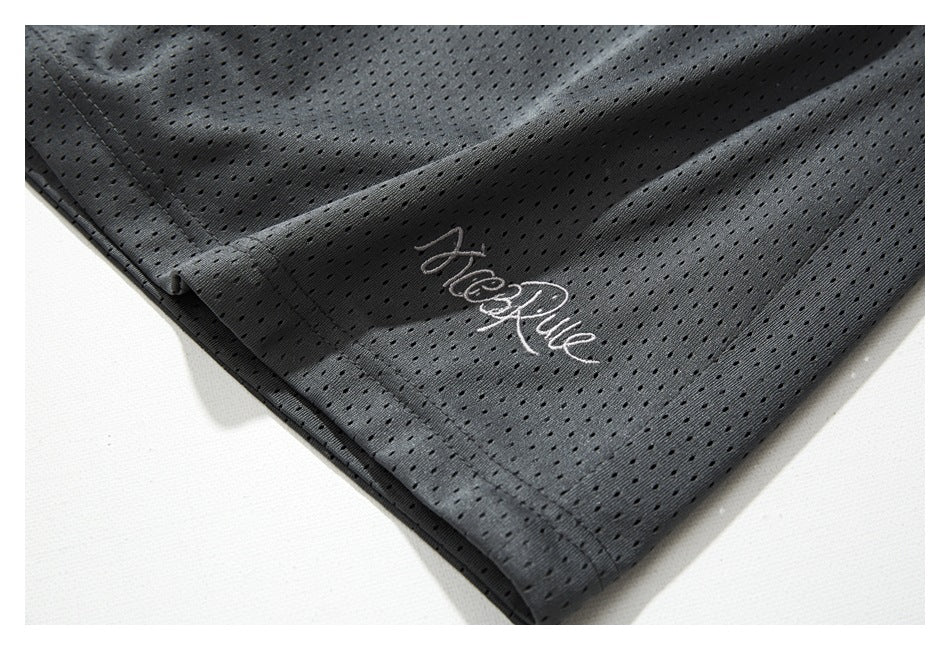 Close-up of the hem of charcoal perforated shorts with small embroidered script.