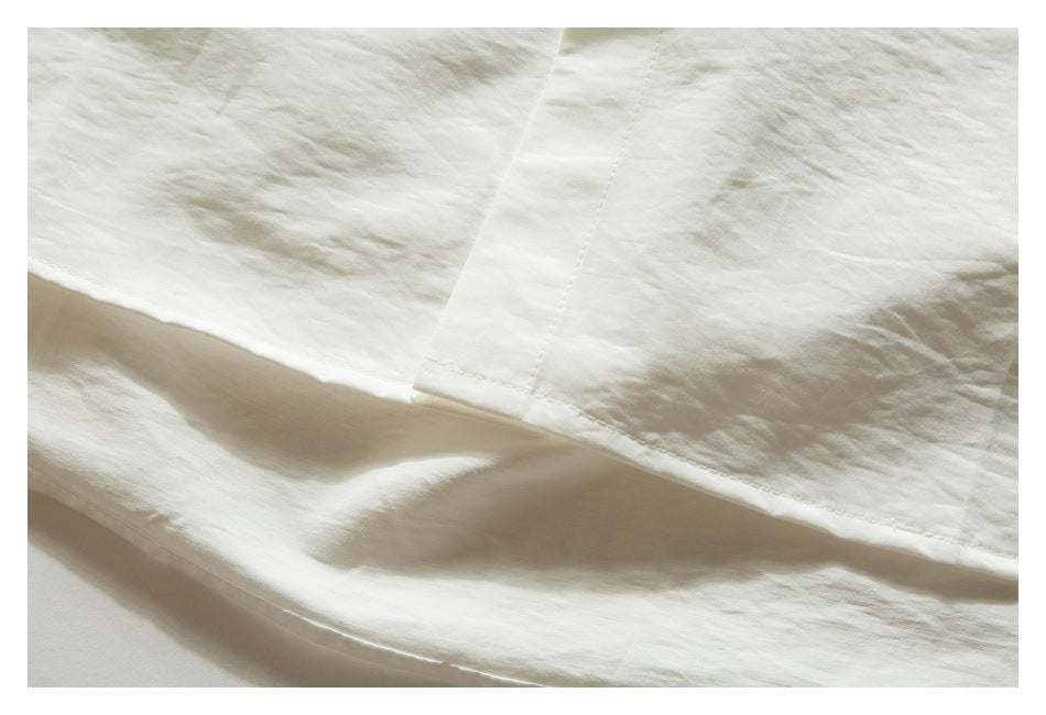 Close-up of white garment fabric with a stitched seam and layered hem.