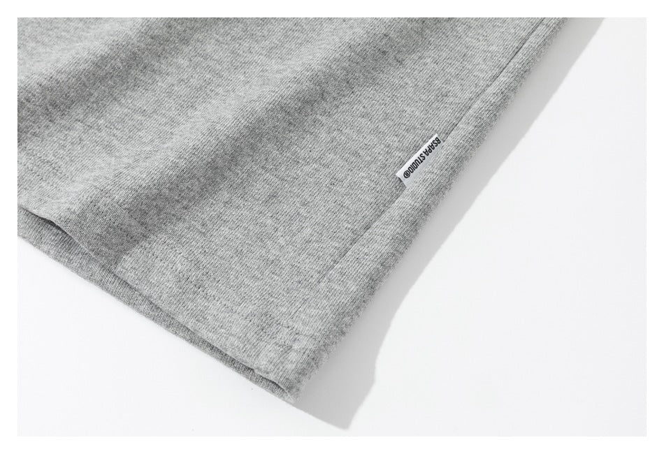 Close-up of the gray sweatshirt's lower hem with a small sewn-in side tab.