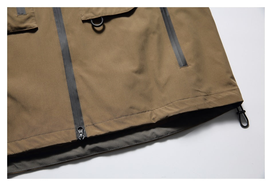 Close-up of the tan jacket's lower front, showing the hem, center zipper and adjustable side toggle.