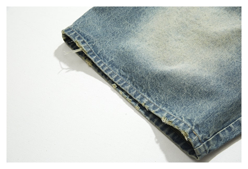 Close-up of a faded blue denim leg with a distressed, frayed hem.