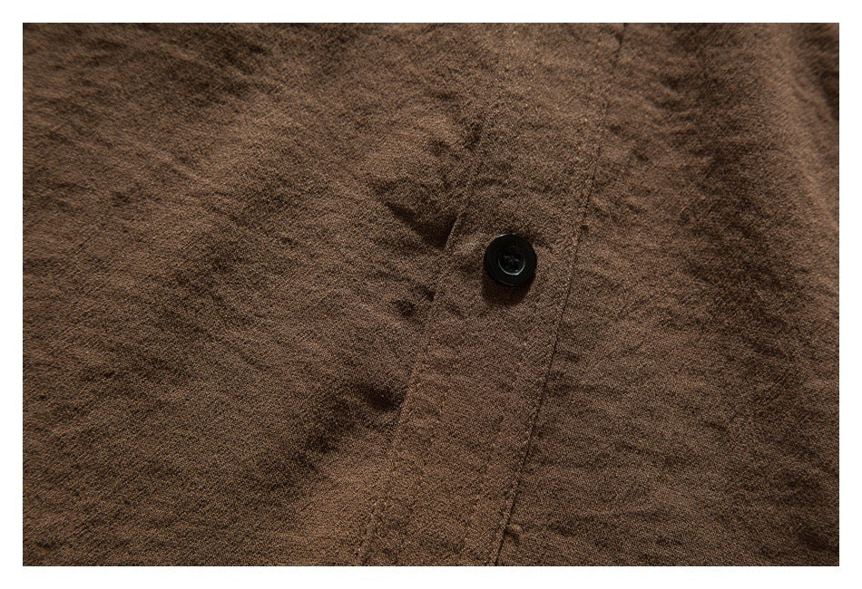 Close-up of brown shirt fabric, a black button, and the front placket seam.
