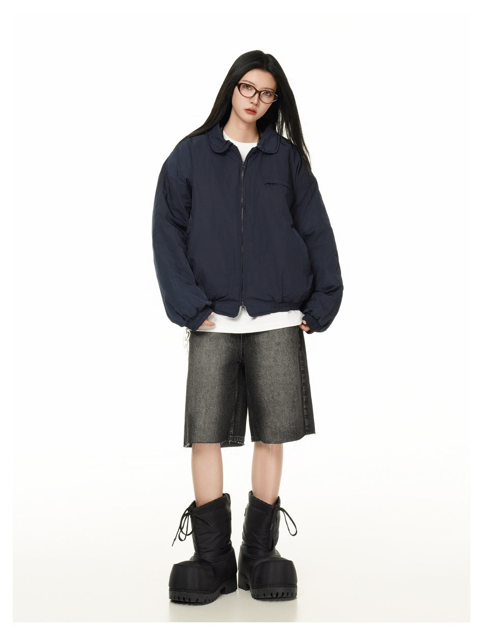 Full-length view of a model in a navy zip jacket with gray denim shorts and black boots