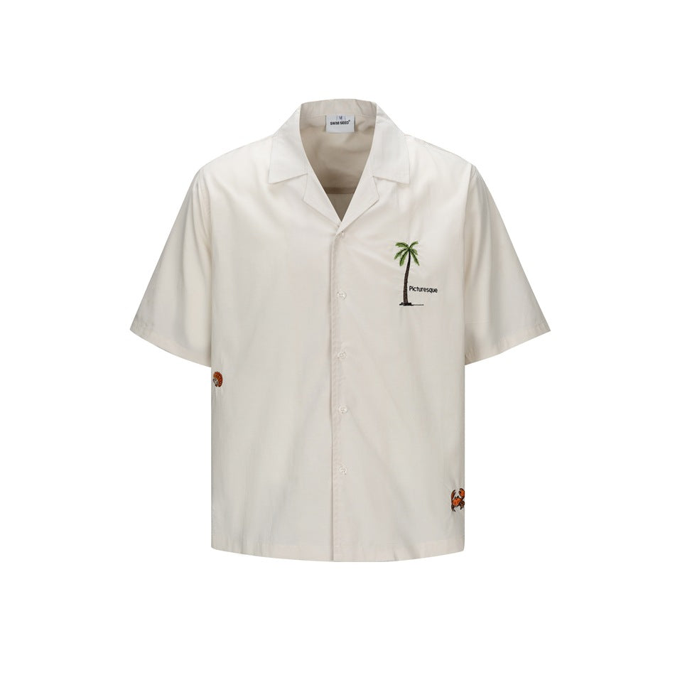 Beige short-sleeve camp collar shirt, front view, with embroidered palm tree and Picturesque text on the chest