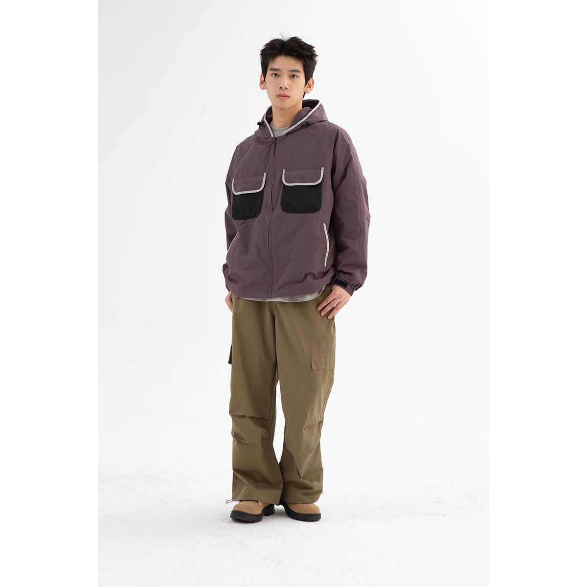 Full-length front view of a model wearing a plum hooded jacket with black chest pockets and olive cargo pants.