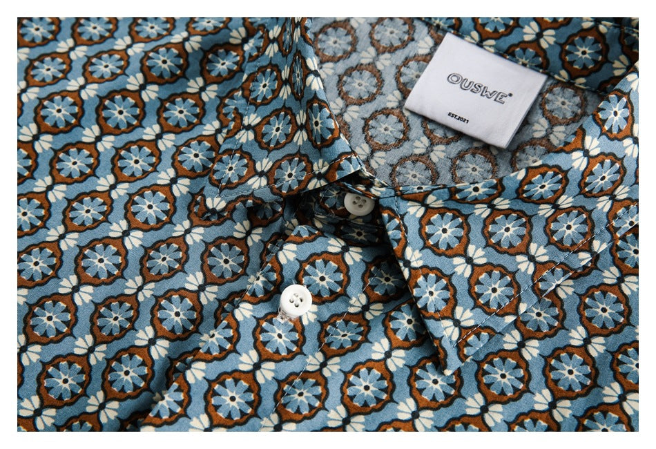 Close-up of the shirt collar, white buttons, and sewn neck label against its blue floral pattern.