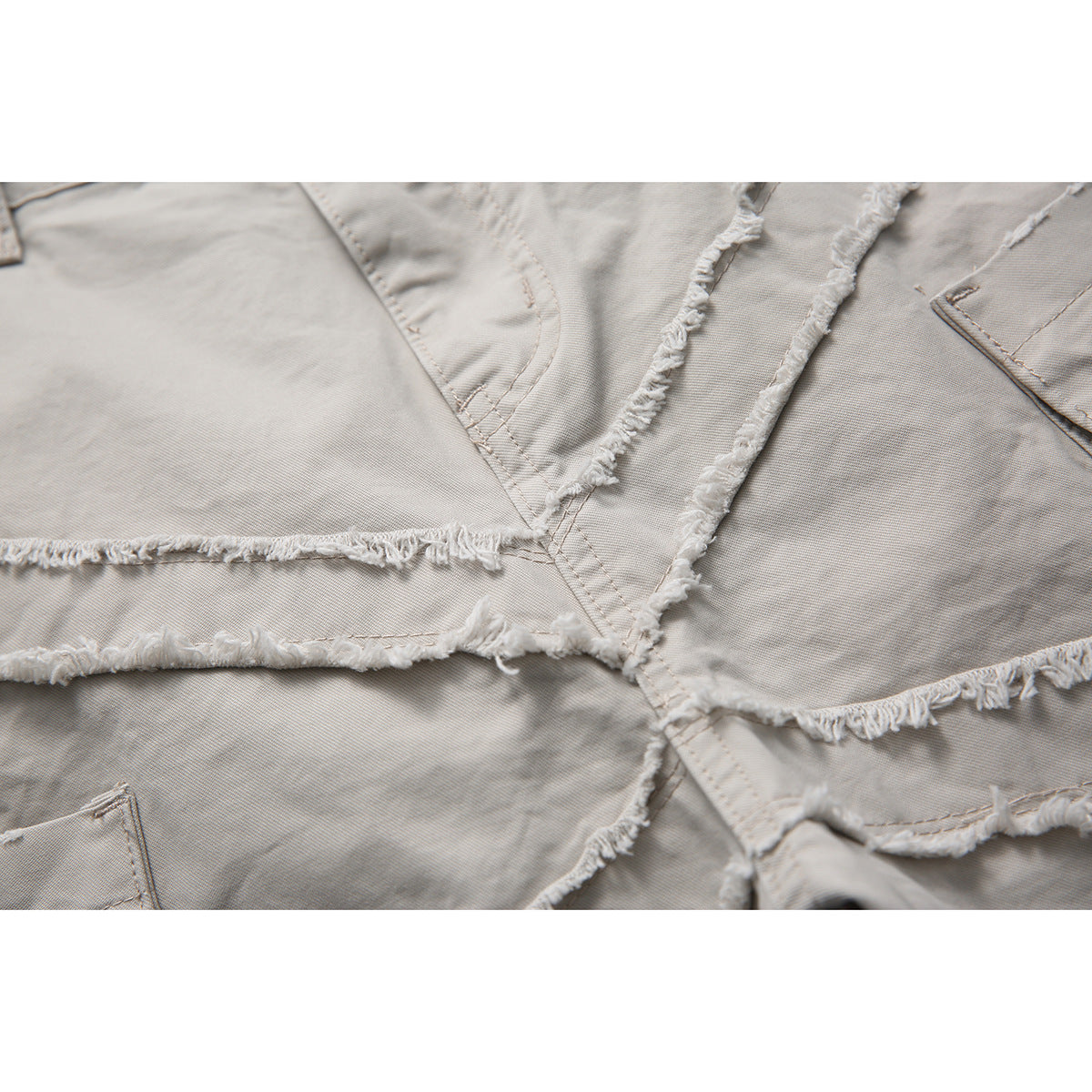 Close-up of light gray shorts showing intersecting seams with raw, frayed edges.