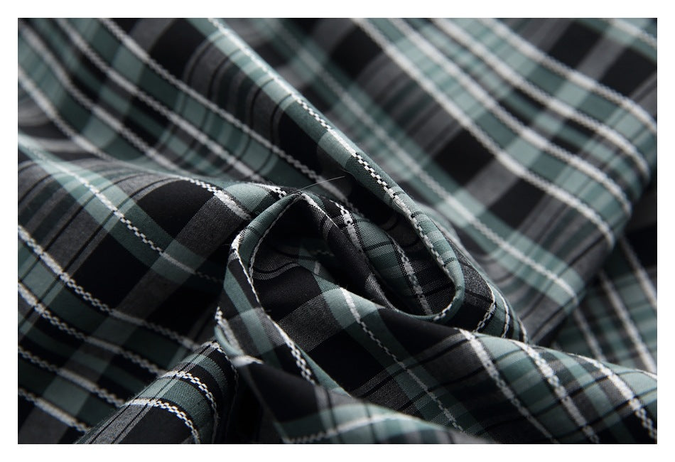 Close-up of dark green, black, and white plaid fabric folded into soft folds.