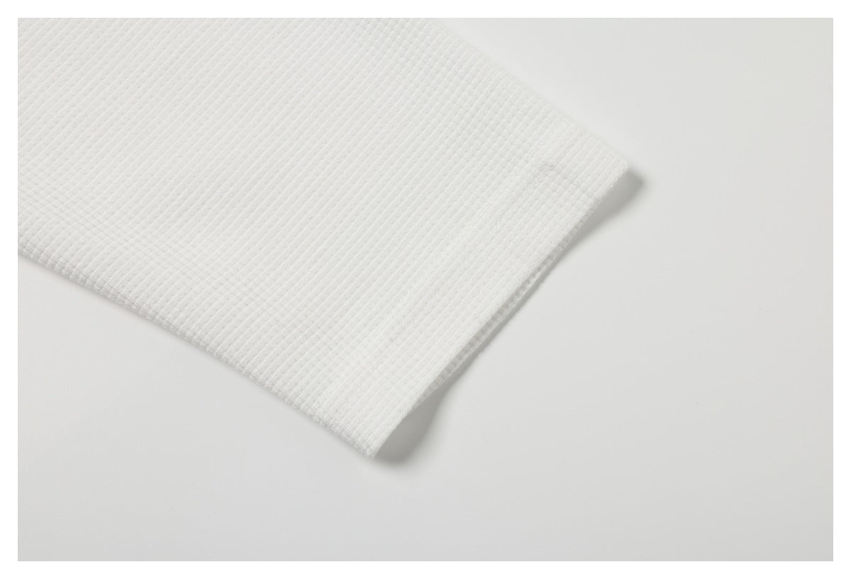 Close-up of a folded edge on a white garment with a subtle ribbed texture.