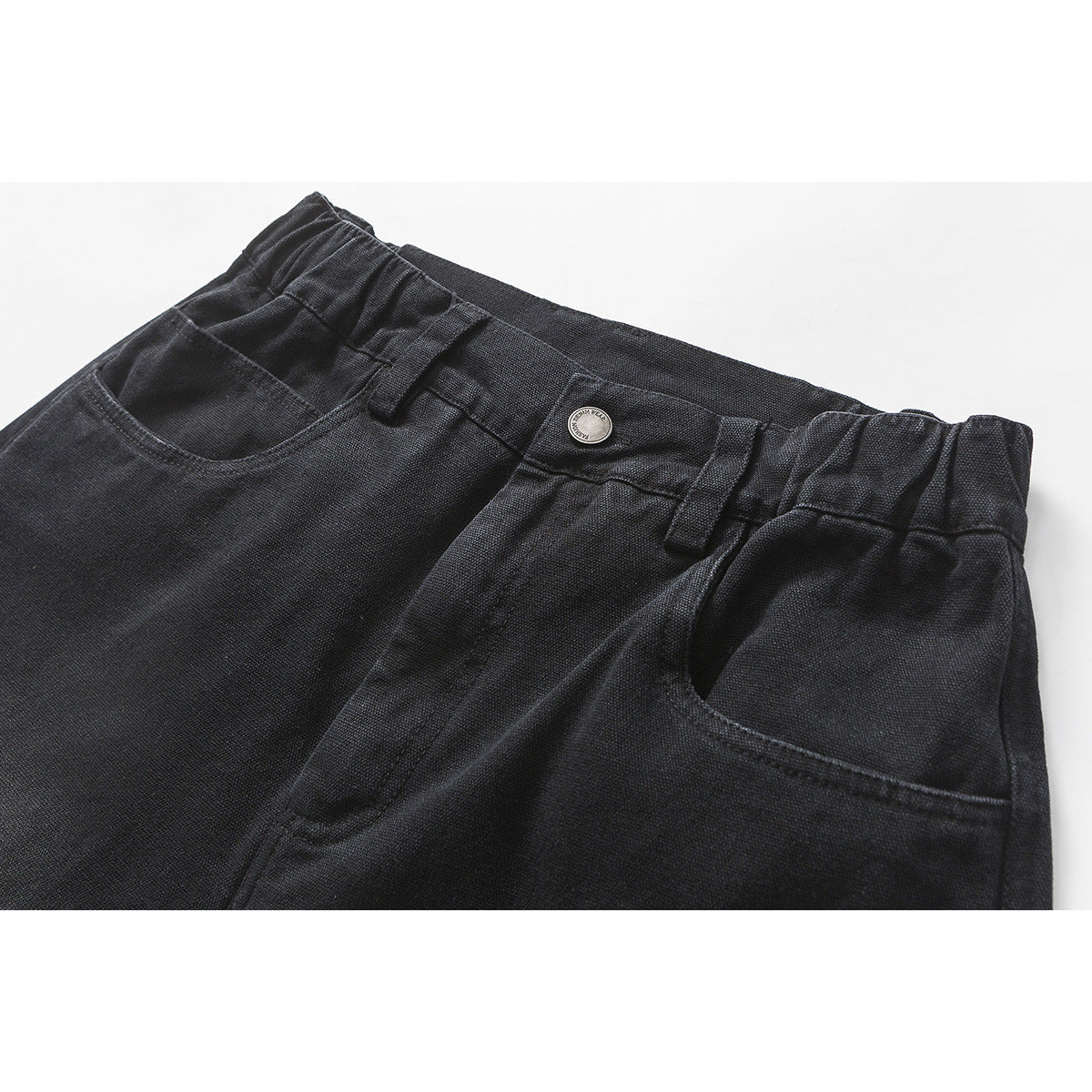 Close-up of charcoal black shorts showing the elasticated waistband, button, belt loops and front pockets.