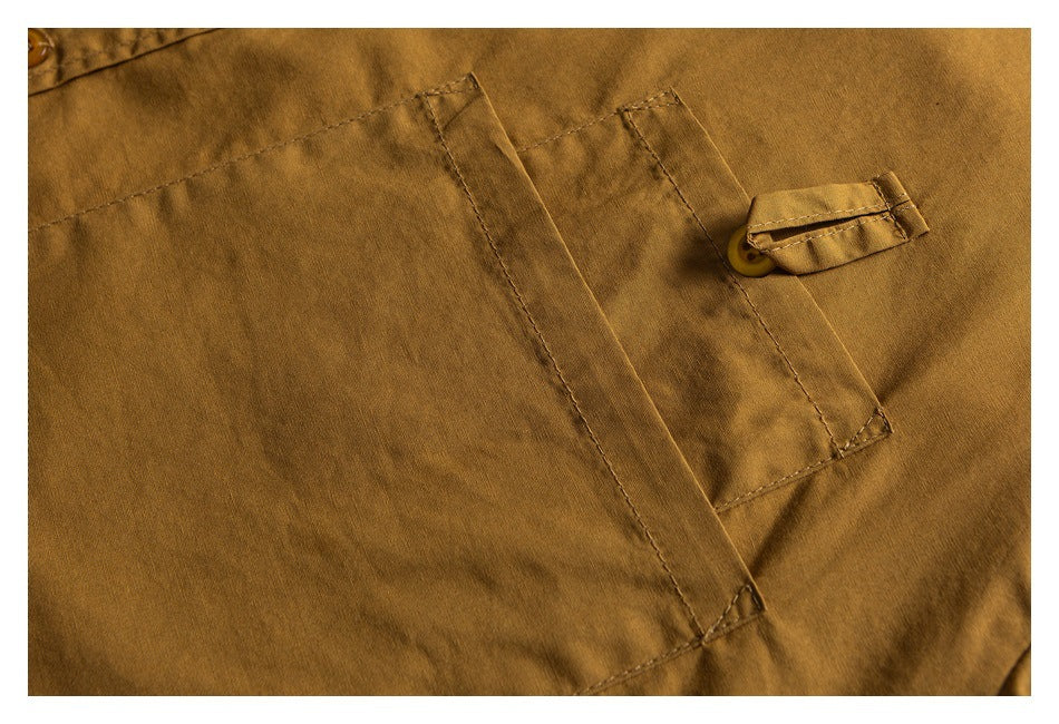 Close-up of a mustard shirt's chest pocket with a buttoned flap and visible stitching.