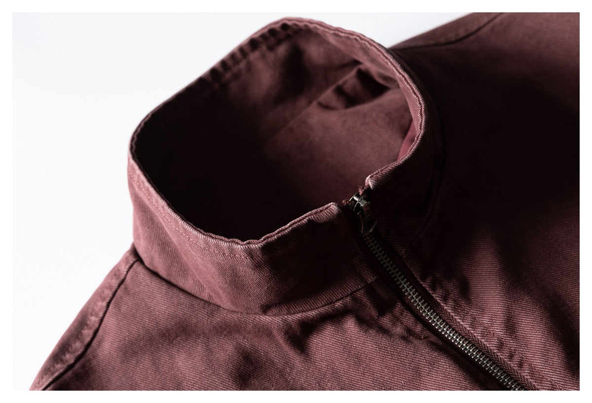 Close-up of a burgundy garment's tall collar and partially open dark metal zipper.