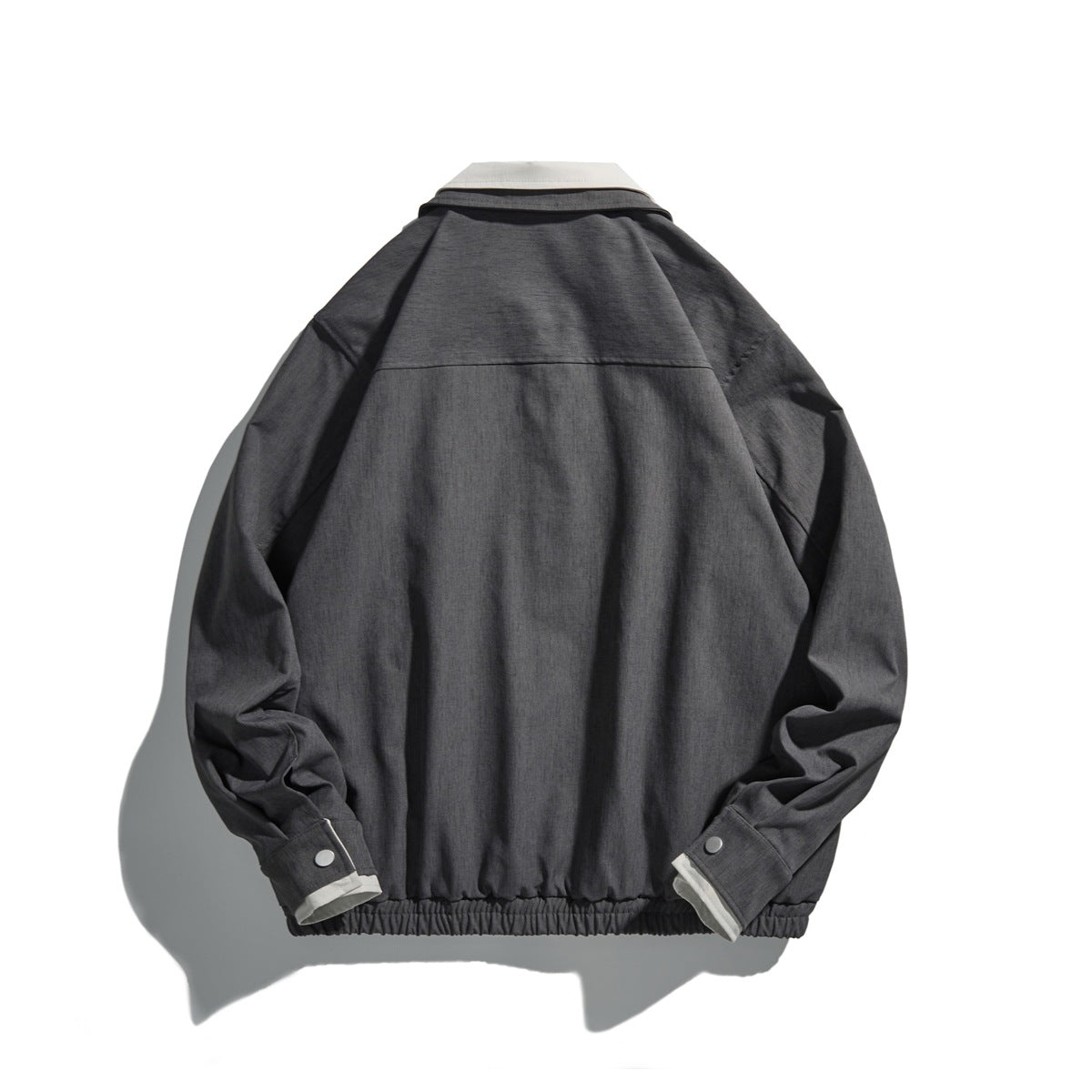 Back view of medium gray collared jacket with back yoke seam, snap cuff tabs and elastic hem, flat lay