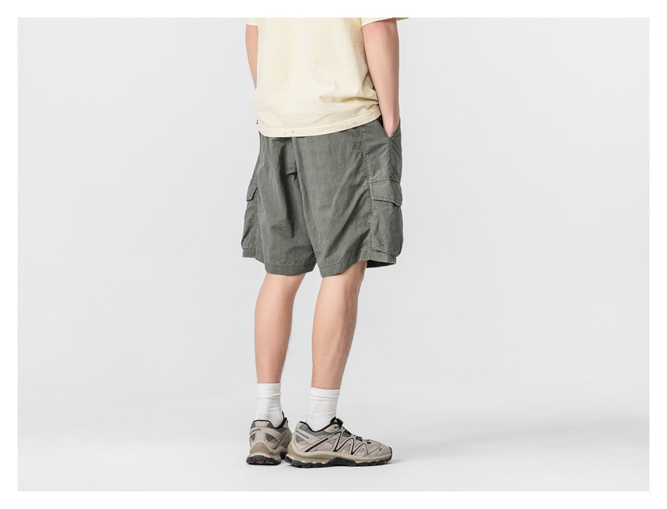 Back view of a model wearing dark gray-green cargo shorts with flap pockets at the sides.