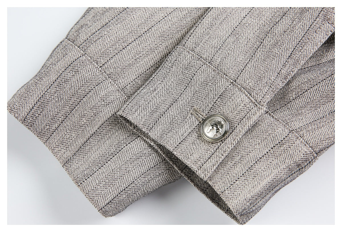 Close-up of a stitched tab with an ornate silver-tone button on gray-beige patterned fabric.