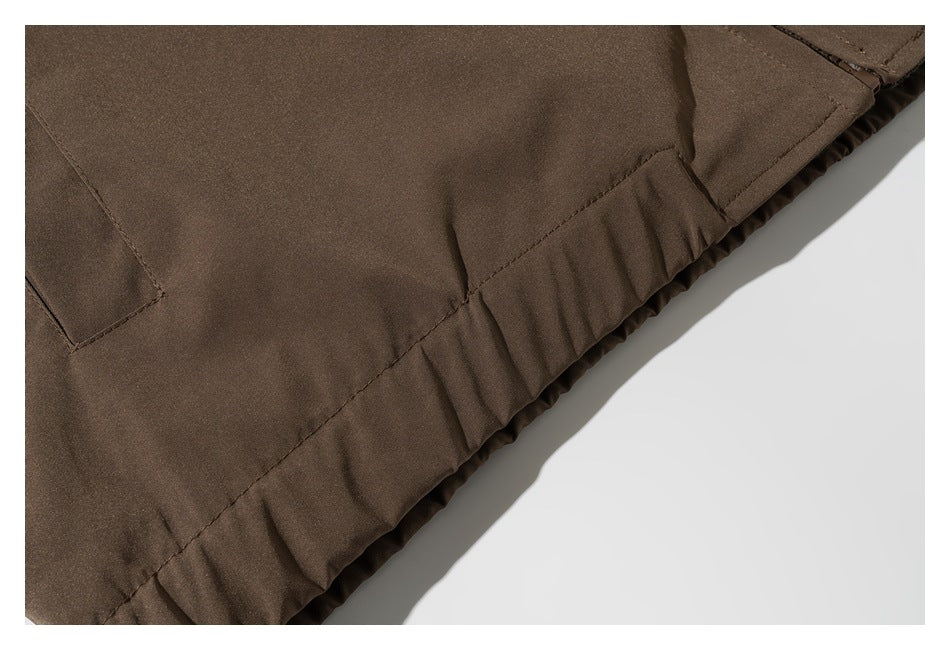 Close-up of a brown garment hem with stitched panels and a gathered edge.