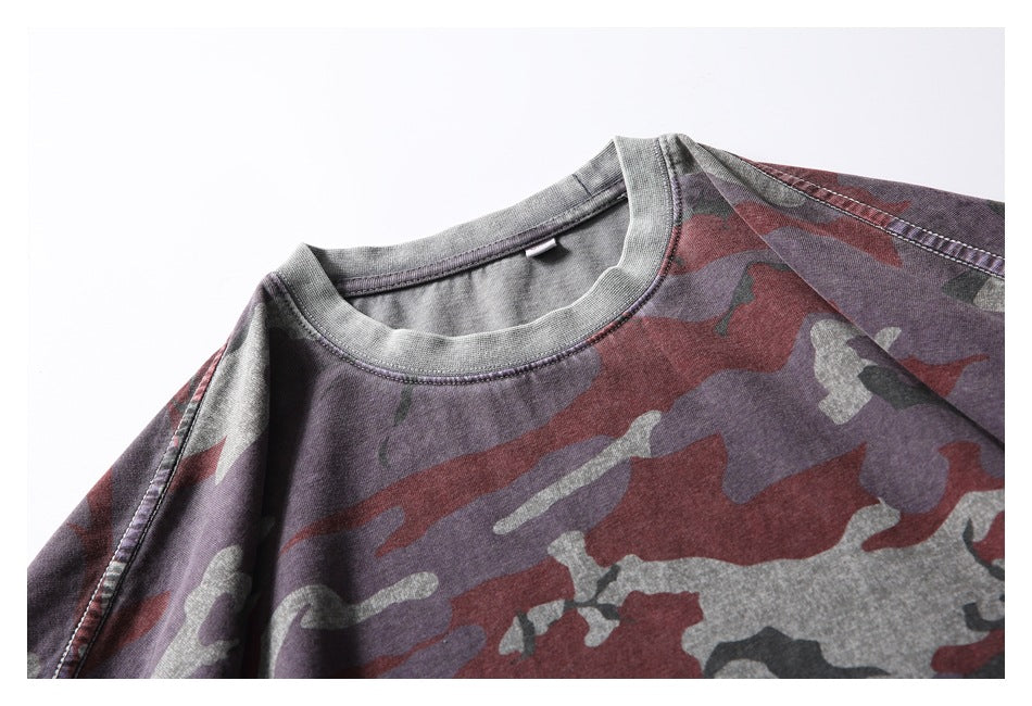 Close-up of the crew neckline and shoulder seams on a burgundy, gray, and purple camouflage T-shirt.