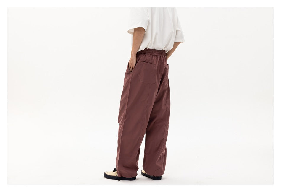 Rear-side view of a model wearing loose mauve cargo pants with an elastic waist and back pockets.