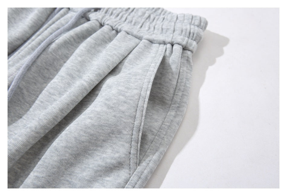 Close-up of a curved side pocket and gathered waistband on light gray sweatpants.