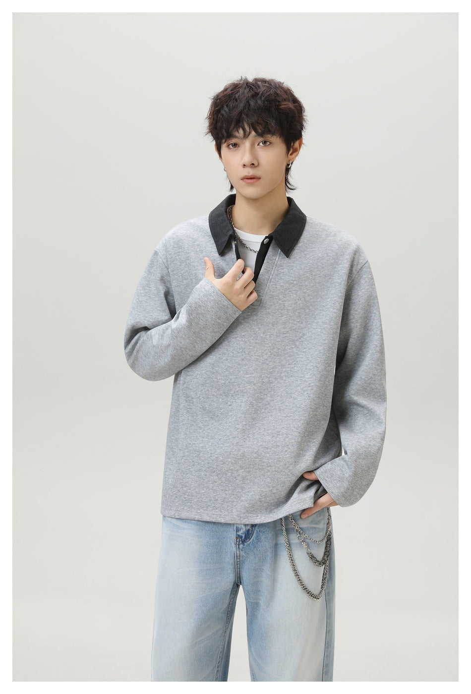 Model wearing a heather gray collared pullover with charcoal collar, white inner layer, and light-wash jeans with chains