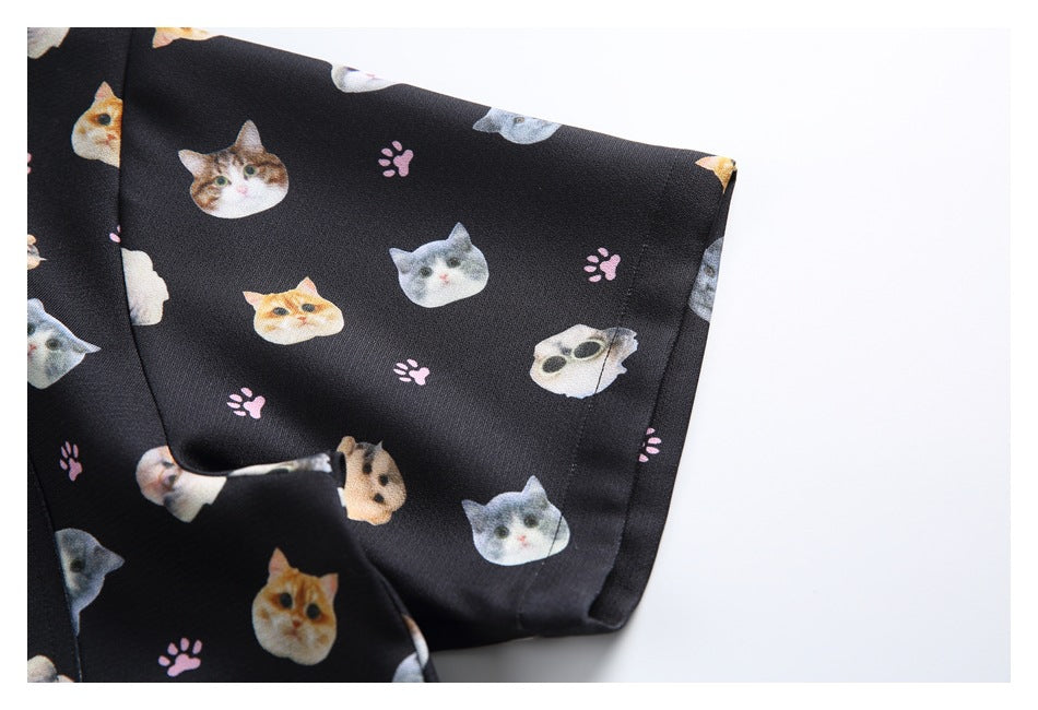 Close-up of the short sleeve and cuff of a black shirt with cat faces and pink paw prints.