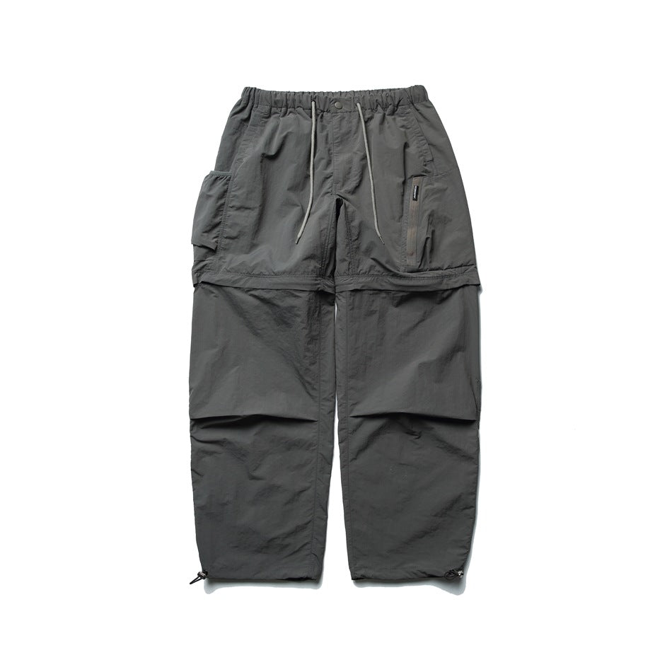 Dark gray wide-leg convertible cargo pants with drawstring waist, zip-off legs and side pockets, flat front view