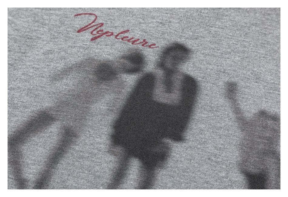 Close-up of a gray sweatshirt's blurred silhouette graphic and red cursive lettering.
