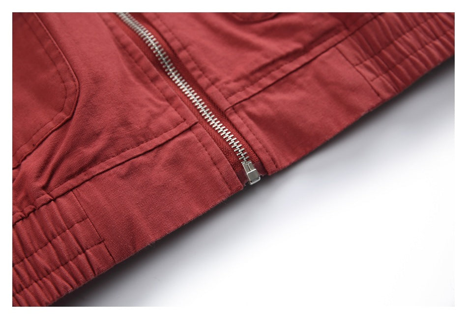 Close-up of the brick-red jacket's central metal zipper and gathered elastic hem.