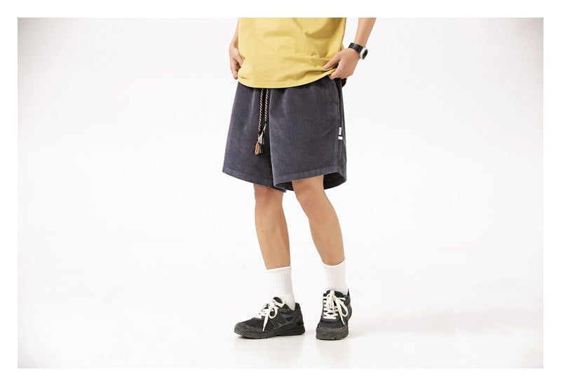 Cropped front view of a model wearing charcoal loose shorts with a tasseled drawstring.