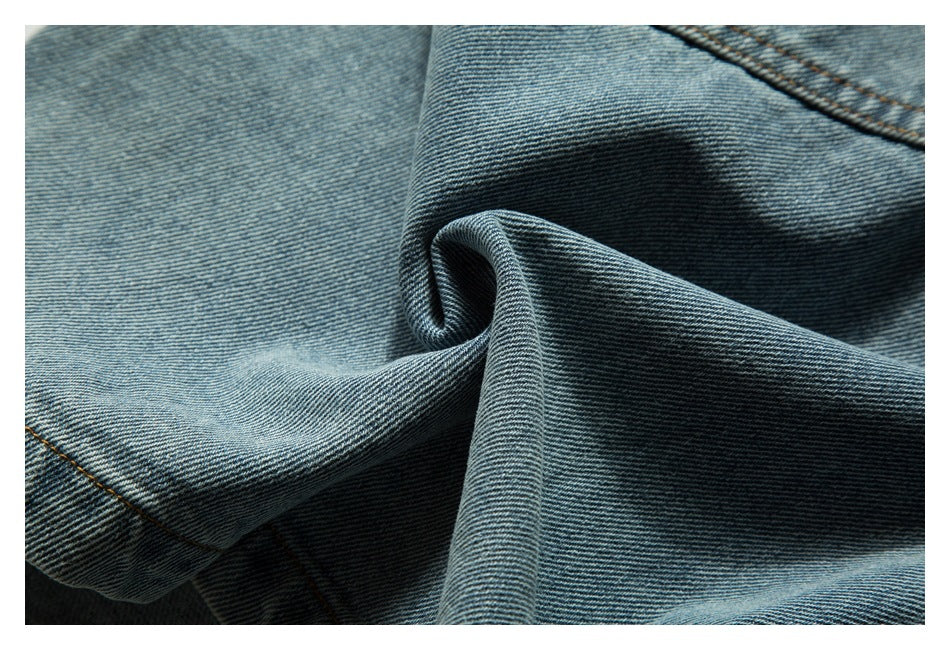 Close-up of folded blue denim fabric with diagonal twill texture and contrast stitching.