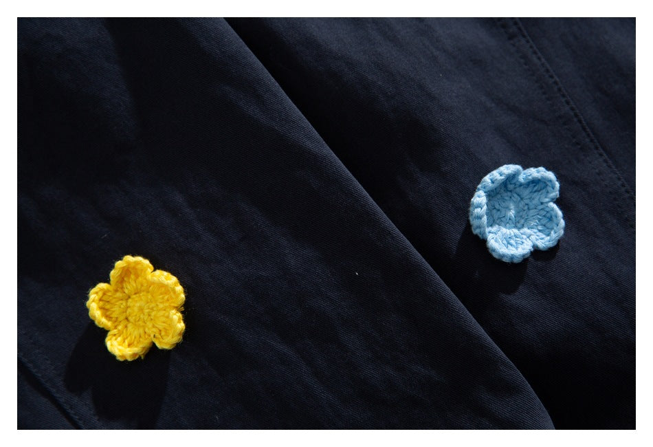 Close-up of yellow and light blue flower appliqués on dark navy fabric.