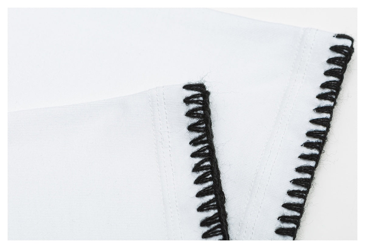 Close-up of white garment panels edged with thick black loop stitching.