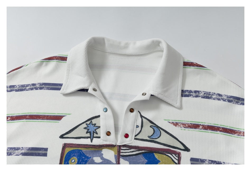 Close-up of the white polo's pointed collar, snap placket, striped shoulders, and colorful chest graphics.