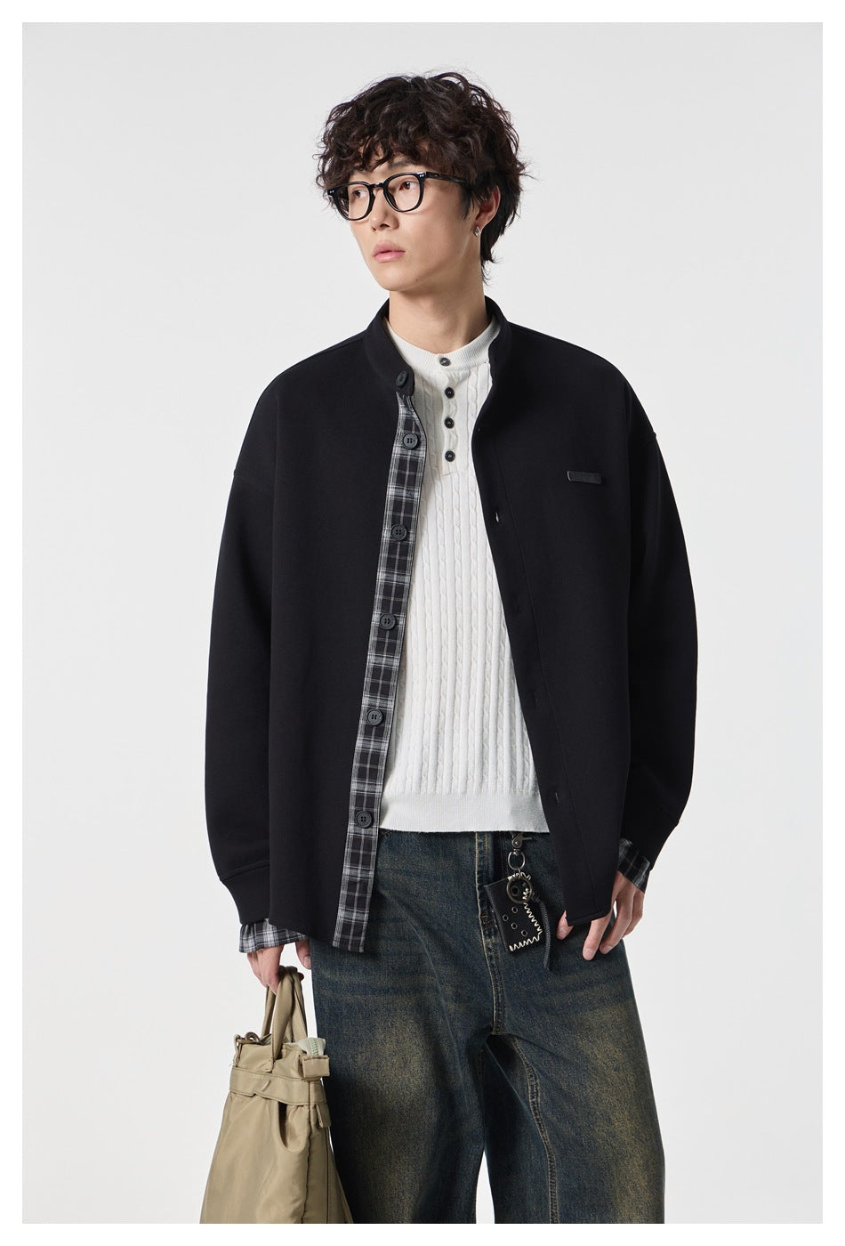Model wearing a black stand-collar jacket with a plaid inner placket and cuffs, shown from the waist up.