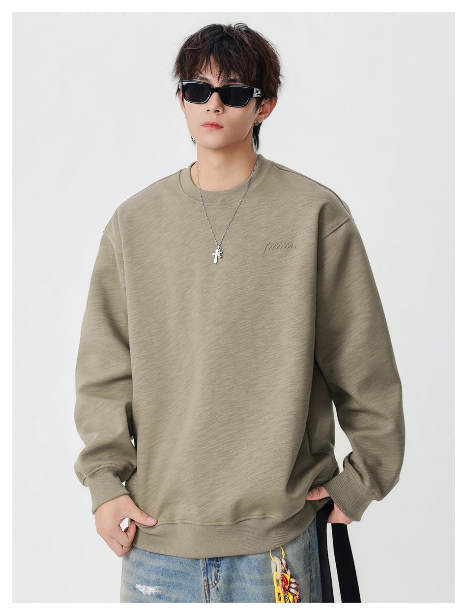 Model wearing a khaki crew neck sweatshirt with drop shoulders, ribbed cuffs and hem, and chest embroidery