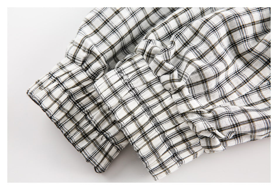 Close-up of folded white fabric with a black and gray plaid pattern and stitched edges.