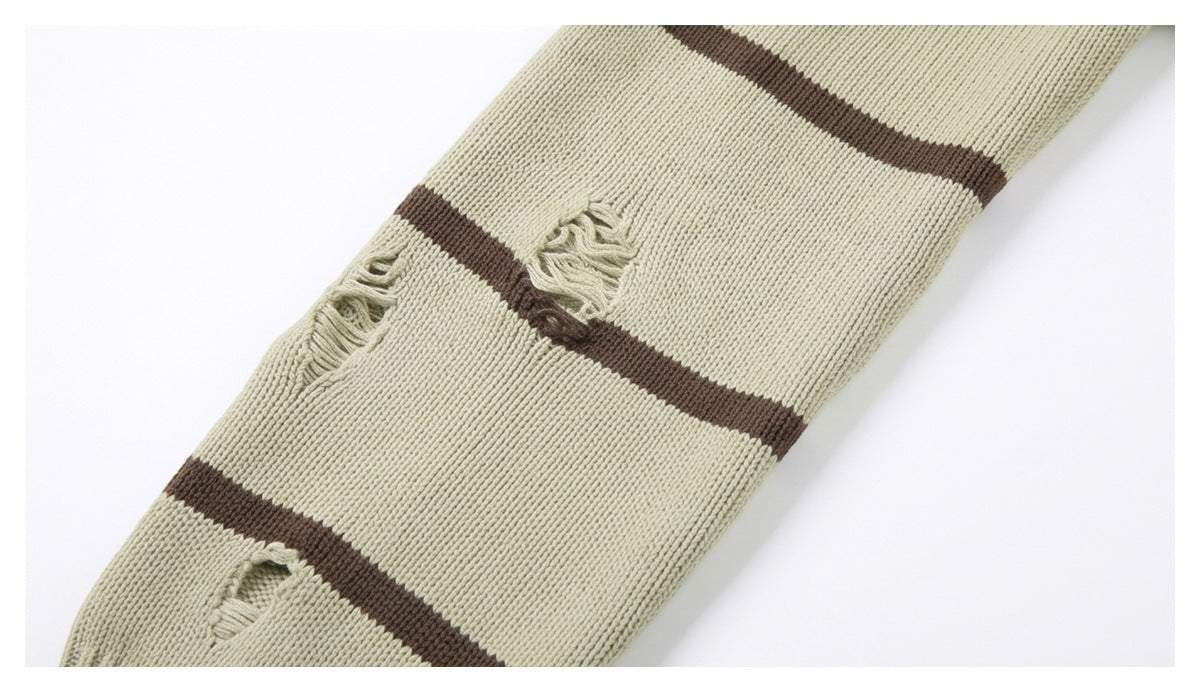 Close-up of a cream rib-knit sweater with dark brown stripes and several distressed holes.