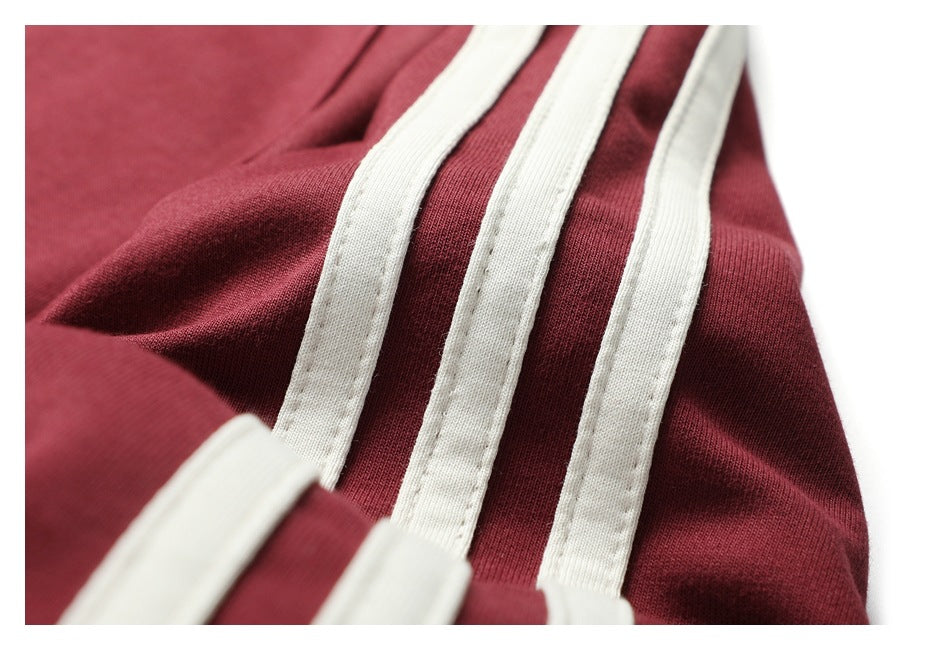 Extreme close-up of three white stripes stitched onto burgundy shirt fabric.
