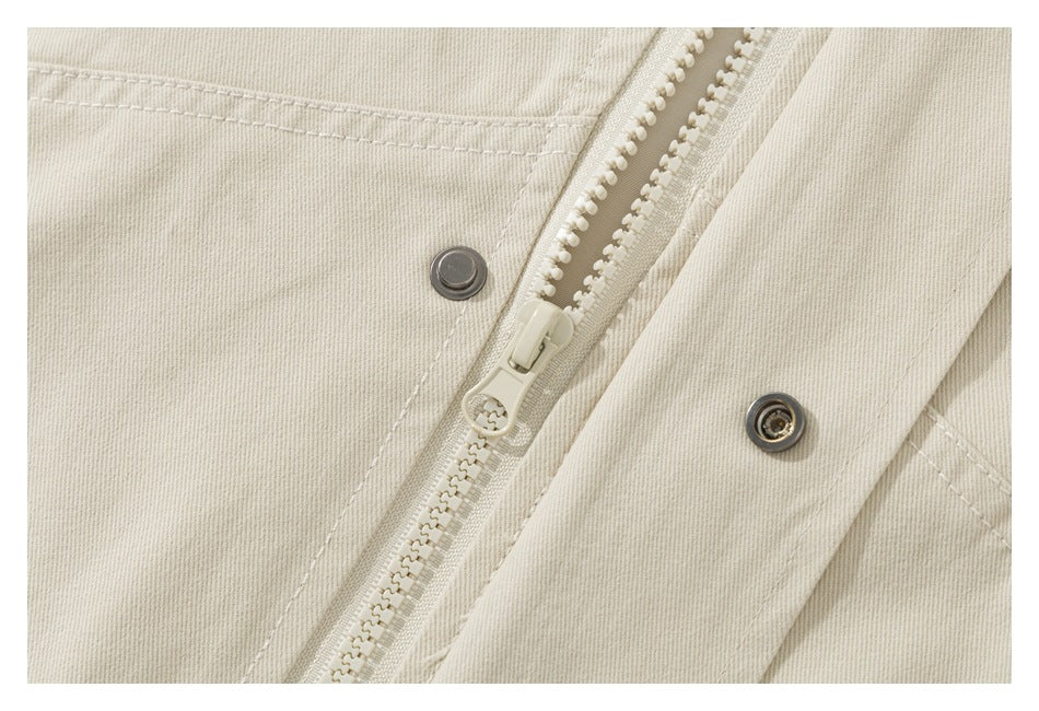 Close-up of the beige jacket's front zipper and snap-button placket.