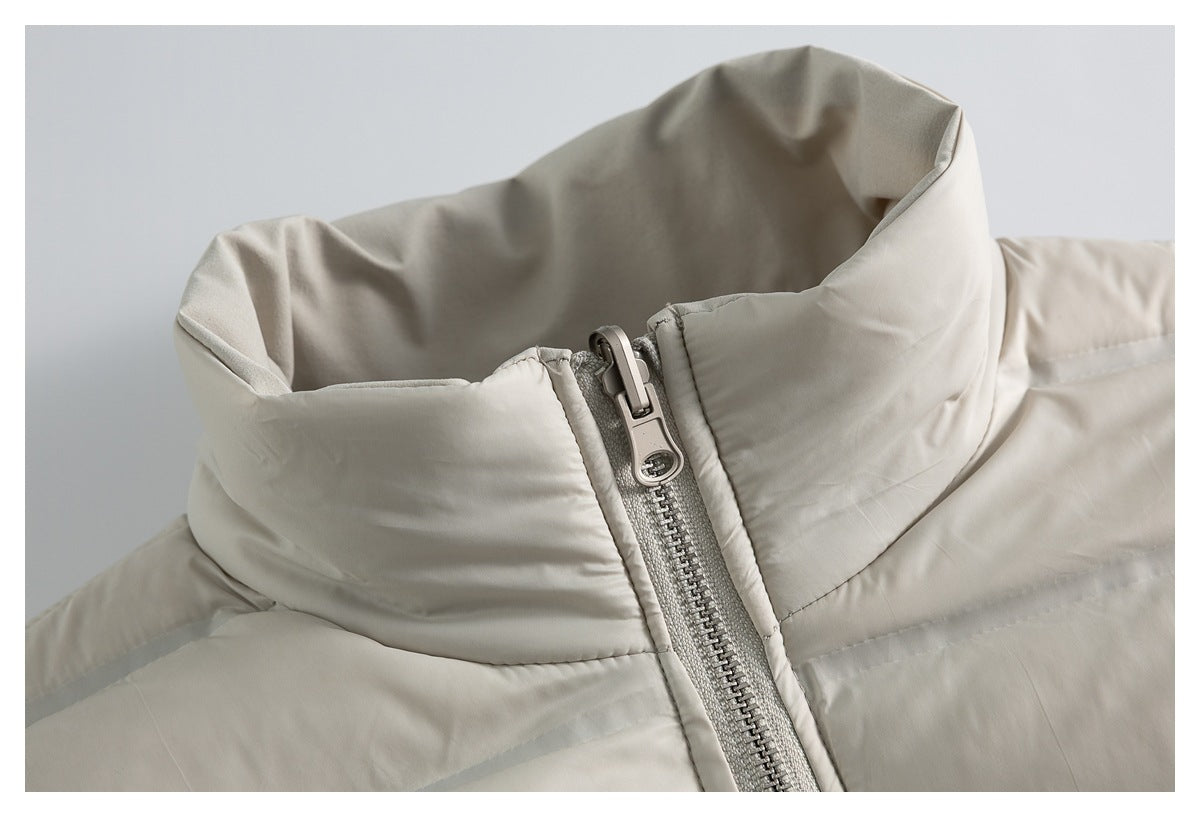 Close-up of a light beige jacket's raised collar and metallic front zipper.
