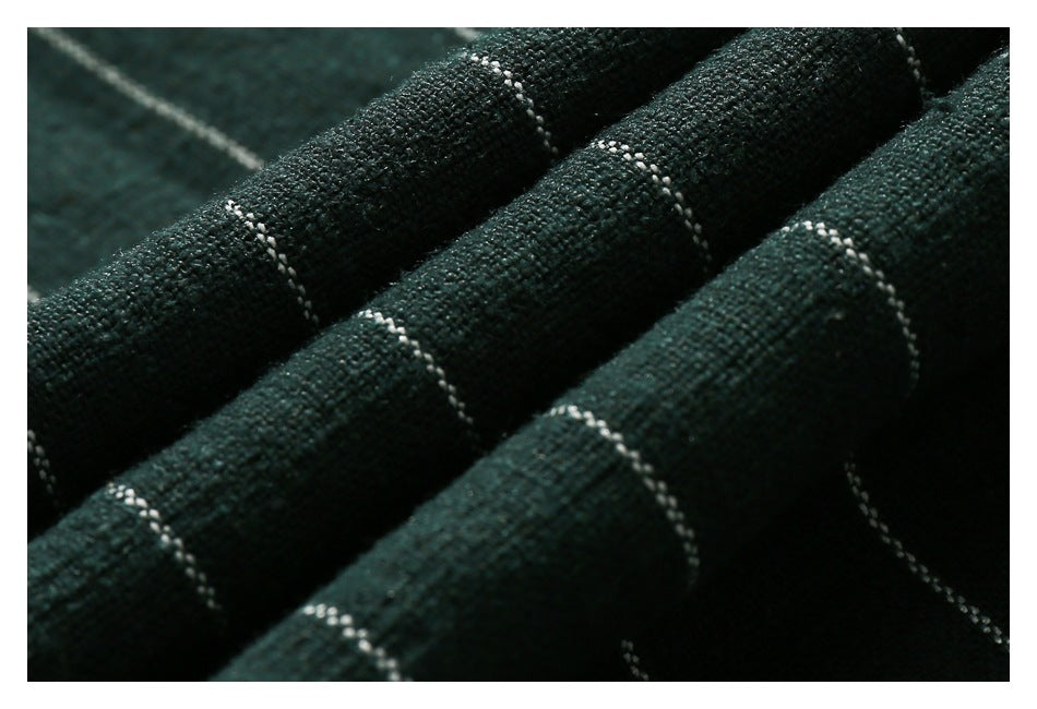 Macro view of dark green striped fabric gathered into soft folds, showing its woven texture.