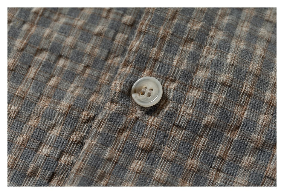 Close-up of a pale button on gray-brown plaid fabric.