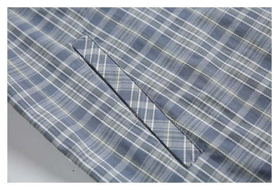 Close-up of an angled welt pocket on the blue-gray plaid jacket.
