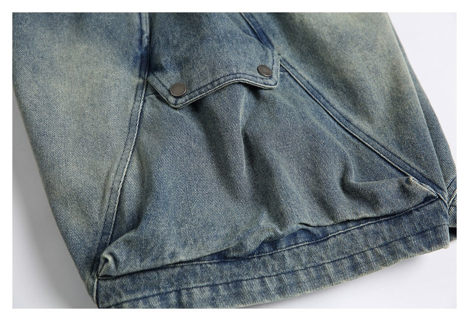 Close-up of a folded denim shorts leg showing a small two-button flap and seam details.