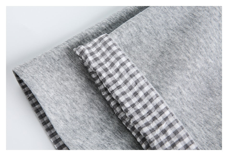 Close-up of light gray marled knit fabric with a gray-and-white gingham edge.