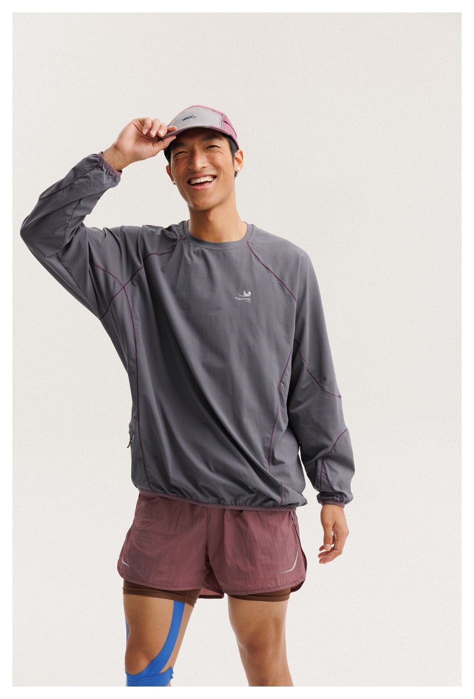 Closer front view of a model wearing a charcoal gray pullover with plum seam details and mauve athletic shorts.