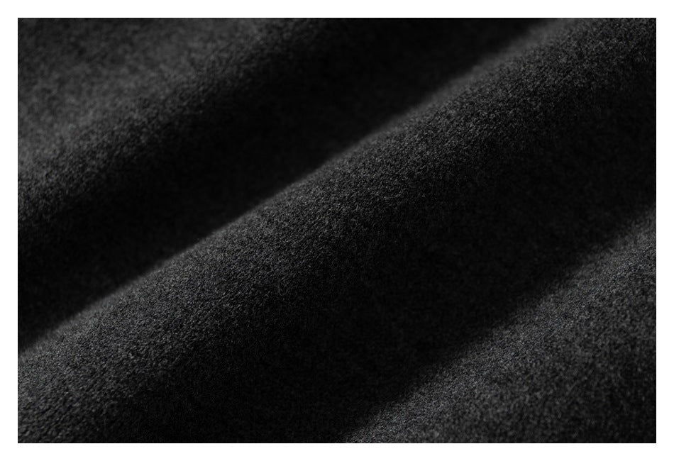 Extreme close-up of the dark charcoal garment's textured surface and folds.