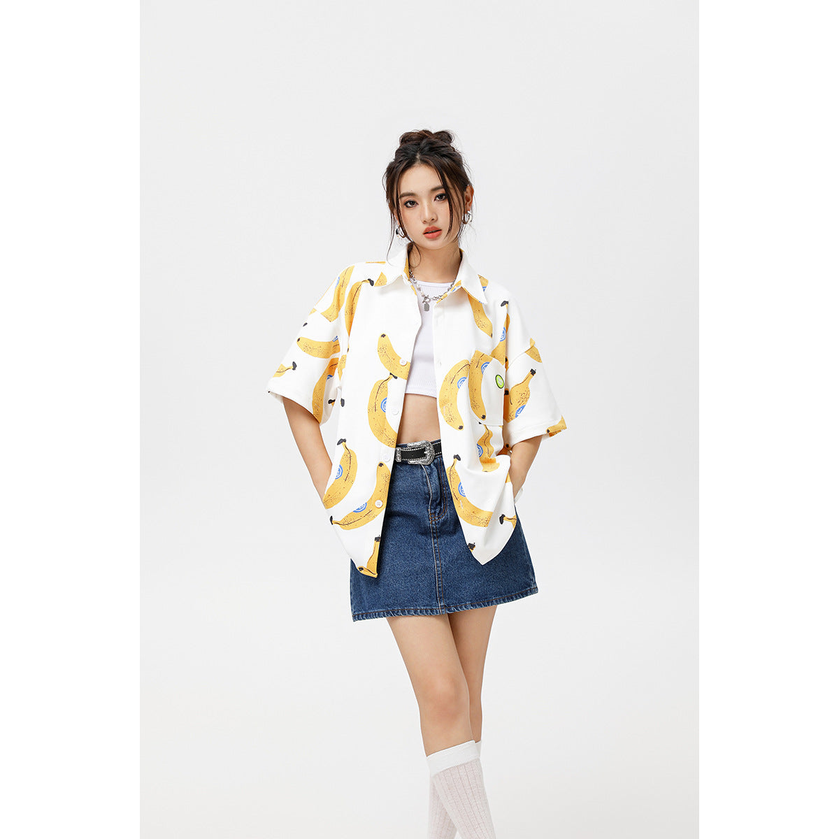 Closer front view of a model in a white banana-print short-sleeve shirt layered over a white crop top.