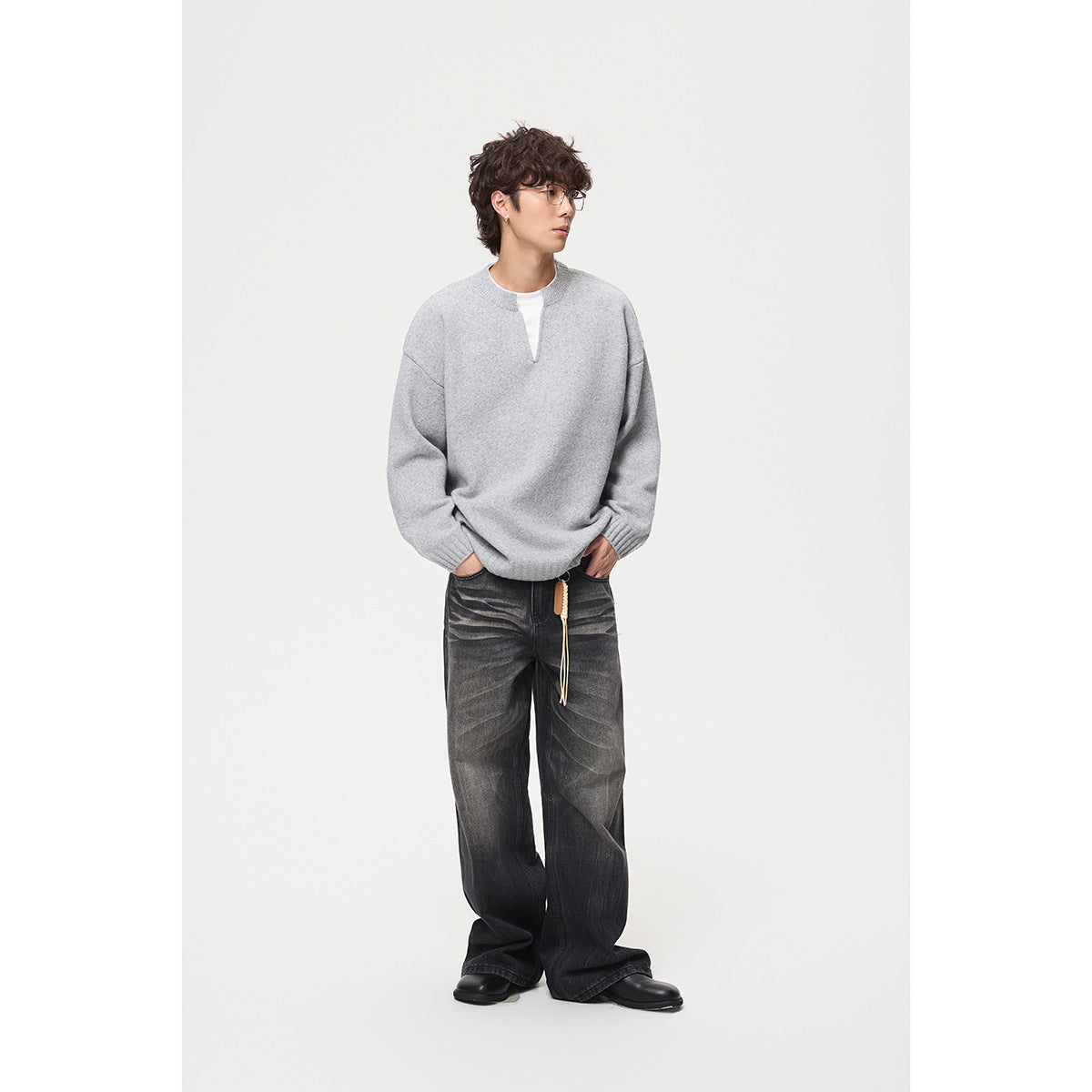 Model wearing a light gray split-neck sweater with ribbed cuffs and hem, paired with dark wide-leg jeans.